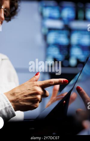 Competent engineers updating data center infrastructure, writing intricate binary code scripts on tablet, using programming to fortify cybersecurity in server farm, close up Stock Photo