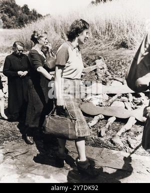 German women from Nammering are forced to walk among the corpses of prisoners exhumed from a mass grave. Actions like this were part of the Denazification process. This process was an attempt to rid Germany and Austria culture and society of nazi influence and ideology. A part of the process included confronting the public with the evidence of the crimes that were carried out in their area. Stock Photo