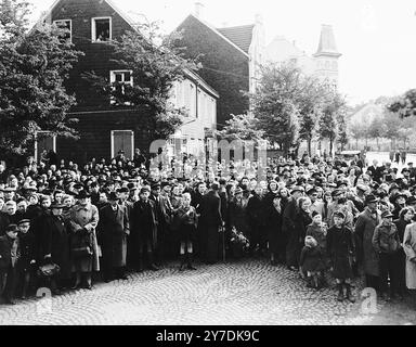 German civilians attend funeral services for the 71 political prisoners, exhumed from a mass grave near Solingen-Ohligs, reburied in front of the city hall. The victims, most of whom were taken from Luettringhausen prison, were shot and buried by the Gestapo following orders to eliminate all Reich enemies just before the end of the war.Actions like this were part of the Denazification process. This process was an attempt to rid Germany and Austria culture and society of nazi influence and ideology. A part of the process included confronting the public with the evidence of the crimes that were Stock Photo