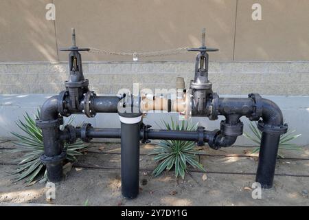 A detailed look at various backflow prevention valves and fire safety systems installed around an industrial site. Stock Photo