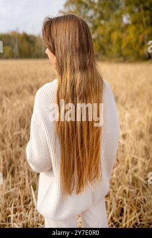 A Beautiful Woman with Long Flowing Hair Standing Gracefully in a Golden Wheat Field Stock Photo