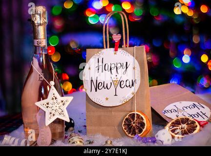 New Year composition. New year holidays card with shopping bag , bottle of сhampagne, festive decorations. Gifts, present, festive bokeh Stock Photo