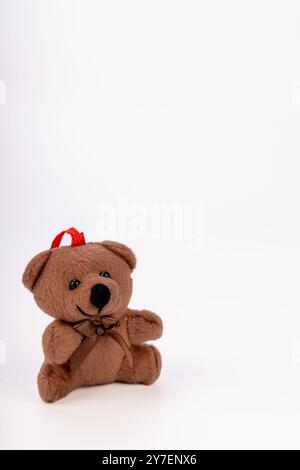 A delightful Christmas teddy bear with a red scarf and Santa hat. Displayed on a white background, this festive decor item adds warmth to seasonal Stock Photo
