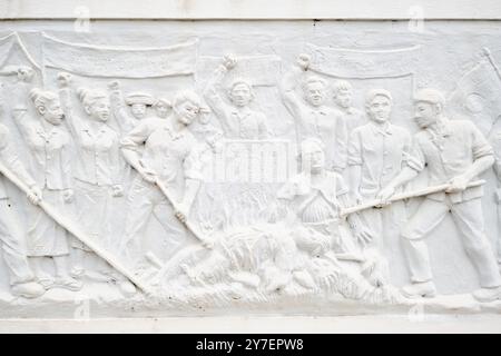 Close up view of a protest, body burning scene on the elaborate marble frieze. At the white marble Revolution Memorial Tower in Vientiane, Laos. Stock Photo