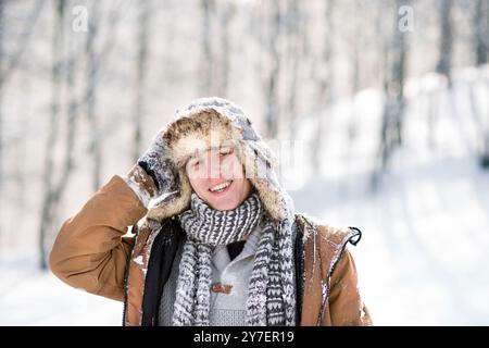 Portrait of young man in the snowy nature, snow stuck to clothes. First snowfall of the season. Stock Photo