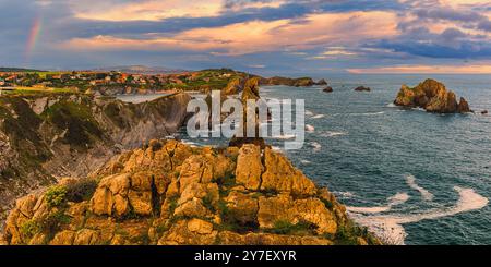 Panoramic sunset and a rainbow at the rock formation of Los Urros de Liencres, part of a fabulous Geology Nature Park in Cantabria in northwestern Spa Stock Photo