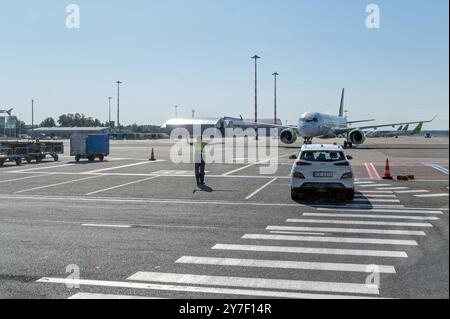 Riga, Latvia - September 7, 2024 : Ground staff signals to an aircraft while a car waits nearby at the airport. Stock Photo