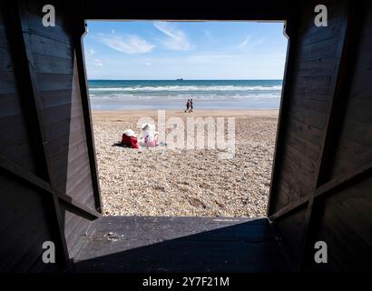 A typical beach scene viewed from inside a beach changing hut, Weymouth, Dorset, England. Stock Photo