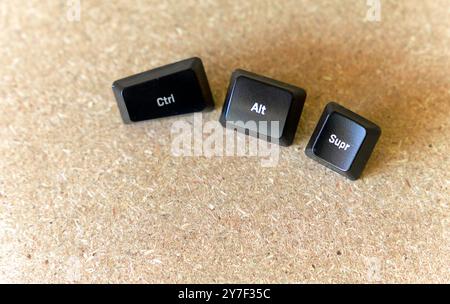 Three black keys are on a wooden surface. The keys are labeled with the letters Ctrl, Alt, and Supr. forced shutdown concept Stock Photo