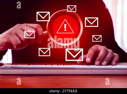 SMS and E-mail spam, danger text message alert concept. Red triangle icon, System hacked error warning sign focus in magnifying glass lens holding by Stock Photo