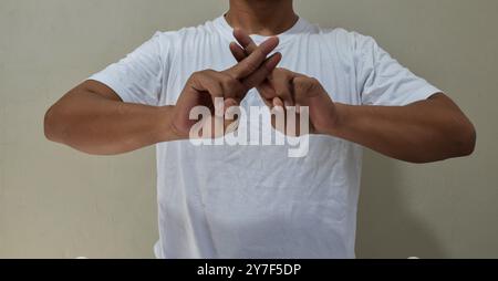 Young man showing fingers gestures, having fun, leading pleasant in american sign language Stock Photo