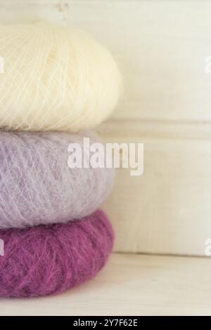 Colourful balls of yarn on white background. Purple and white mohair yarn with copy space. Knitting hobby. Multicoloured yarn. Handiwork store Stock Photo