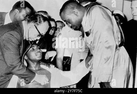 World Heavyweight Champion Sonny Liston (right) and challenger Cassius Clay (seated) exchange unpleasantries as Dr Alexander Robbins (left) examines Clay at the weigh-in. 25th February 1964. Stock Photo