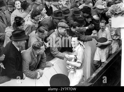 Arsenal captain Joe Mercer holds the FA Cup presented to him by the King as he and other Arsenal players receive the congratulations fom the crowd at Wembley stadium. Arsenal defeated Liverpool 2-0 in the final.  29th April 1950. Stock Photo