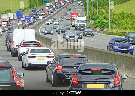 M25 London orbital four lane motorway road uphill nose to tail crawl in sunny summer Friday afternoon traffic jam approaching junction 17 England UK Stock Photo