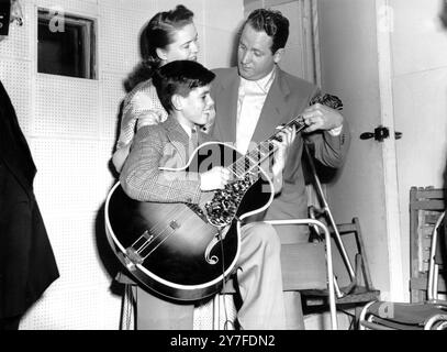 American man and wife guitarists Les Paul and Mary Ford have a few words of encouragement for 14 year old exponent of the electric guitar, Chris Boyle of Edmonton, a student at the Central School of Dance Music. Chris, who has been playing the guitar for three years, wrote to Mary and Les asking them if he could see them. By way of reply they made a special trip to the London Central School of Dance Music. September 24th 1952 Stock Photo