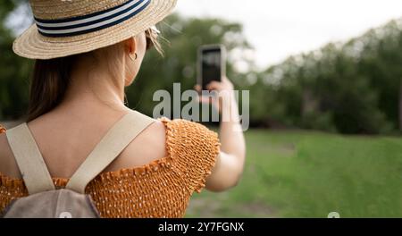 Anonymous female traveler taking picture of landscape with greens and sunset sky on mobile phone during trip in europe Stock Photo