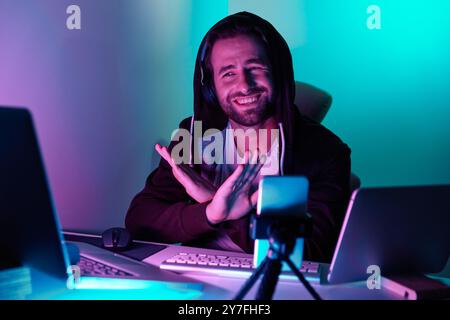 Handsome young man looking at the computer monitor and gesturing against colorful background Stock Photo