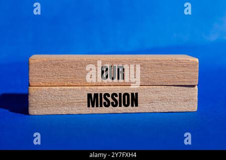 Our mission message written on wooden blocks with blue background. Conceptual our mission symbol. Copy space. Stock Photo