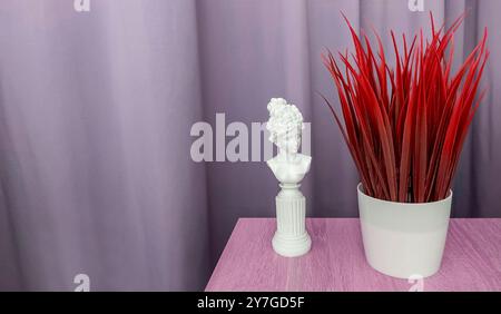 On the table there is a statuette of a female silhouette and artificial grass in a pot Stock Photo