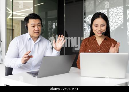 Business colleagues engaged in video conference using laptops and headsets. Professionals communicating and collaborating on projects. Image captures teamwork, technology, communication in office Stock Photo
