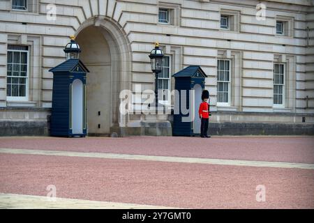 One of the Kings Guards in front of the Palace behind the gates at Buckingham Palace Stock Photo