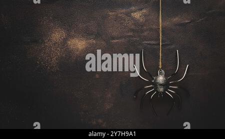 Hanging black glitter spider decoration for halloween, dark grunge gold glitter background, spooky, minimalist night scene, creepy insect suspended in Stock Photo