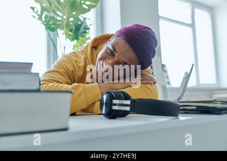 Relaxed mixed race man looking at camera and smiling while sitting at his working place Stock Photo