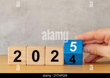 Year 2025. Hand turning 2024 to 2025. Copy space, Happy new year. Business concept related to 2025 Stock Photo
