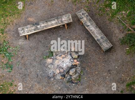 Wooden benches with an outdoor fireplace in nature Stock Photo