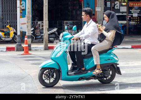 BETONG, THAILAND, MAR 02 2024, A couple is riding a motorbike in the city center Stock Photo