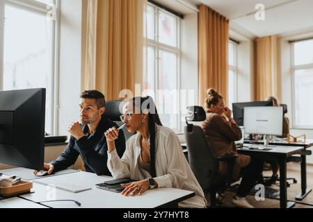 Female and male business professionals sharing computer screen while working in office Stock Photo