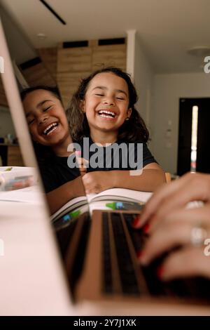 Happy boy laughing with eyes closed while studying at home Stock Photo