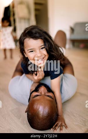 Portrait of happy boy lying on father while having fun at home Stock Photo