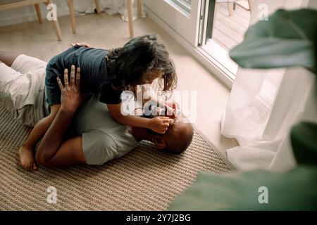 High angle view of boy playing with father's eyes lying down on carpet at home Stock Photo