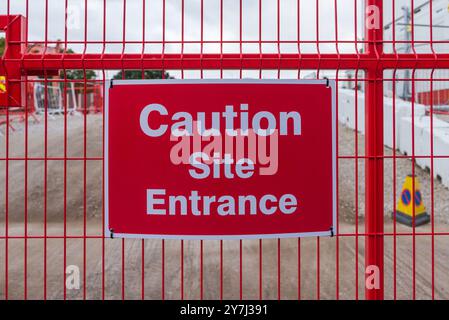 Warning sign on wire fence around building site saying caution site entrance Stock Photo