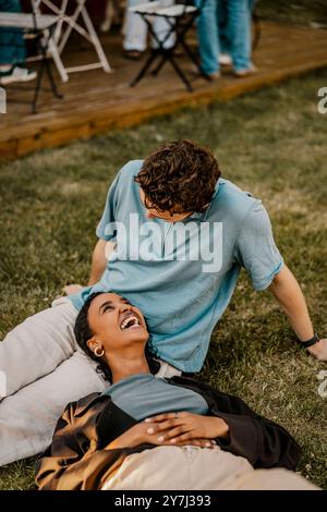 High angle view of happy woman lying down on lap of male friend sitting on grass in back yard Stock Photo