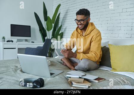 Happy African man using technologies while sitting on the bed at home Stock Photo
