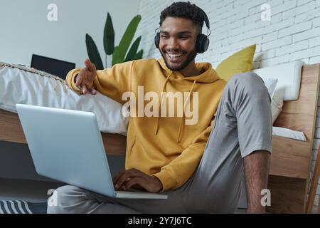 Cheerful African man having web conference and gesturing while sitting on the floor at home Stock Photo