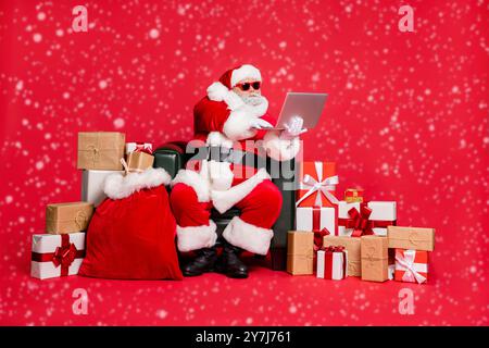 Nice focused hard-working fat bearded man sitting delivering many different purchases shop delivery checking address list wi-fi clients isolated on Stock Photo