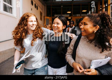 Happy multiracial female students walking on school campus Stock Photo
