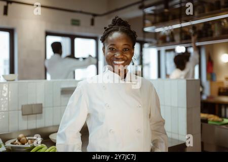 Smiling young female chef at commercial kitchen in restaurant Stock Photo