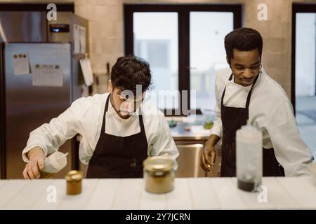 Male chefs working together in commercial kitchen at restaurant Stock Photo