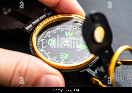 A close-up image of a compass held in hand, representing travel direction, navigation, adventure, and exploration in outdoor activities and hiking tri Stock Photo