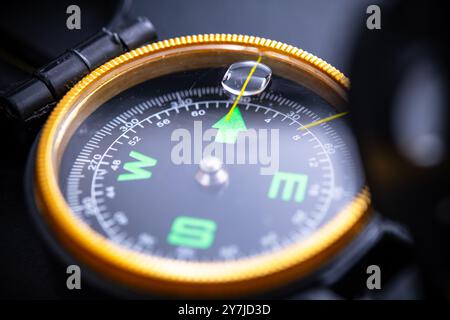 Close-up view of a compass on a black background, symbolizing navigation, adventure, camping, and outdoor exploration. Ideal for travel enthusiasts an Stock Photo