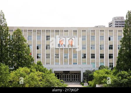 Pyongyang, North Korea - July 26, 2015: Distinctive portraits of Kim Il Sung and Kim Jong Il adorn the facade of a government building in Pyongyang, s Stock Photo