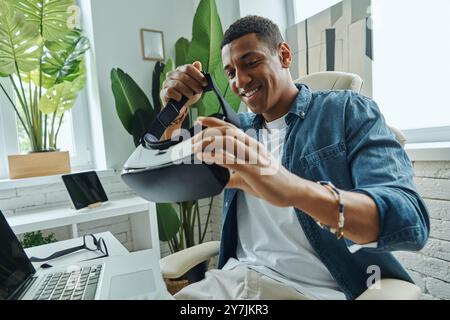 Confident mixed race man examining virtual reality glasses while sitting at the desk Stock Photo
