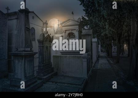 Old european cemetery street  in a cloudy full moon night. Stock Photo