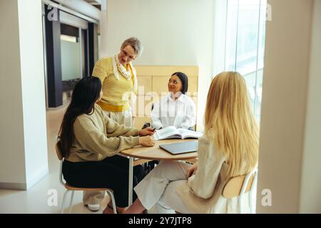 Diverse group of college students studying together in a city campus library. Engaged in discussion and teamwork, enhancing learning experience. Stock Photo