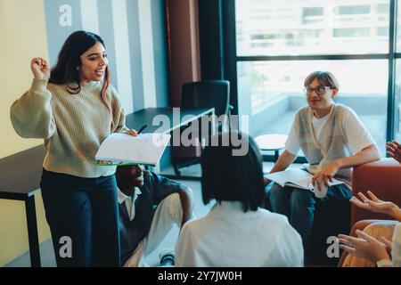 A student confidently presents a project to classmates in a modern classroom environment, with an engaged and attentive audience. Stock Photo